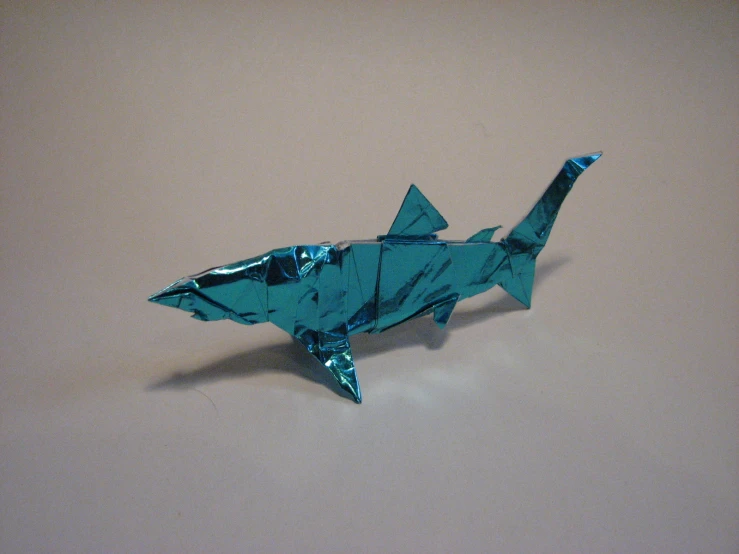 a folded blue origami shark laying on top of a table