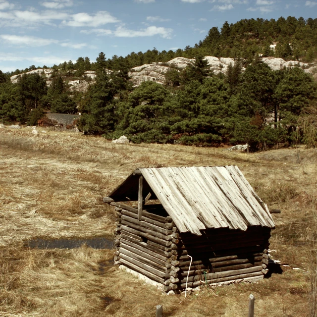 an old log cabin in a grassy field