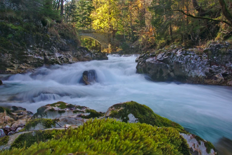 a flowing river with a bridge in the background