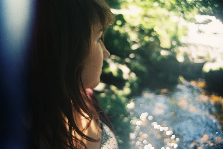 a close up of a girl with flowers on her face looking out a window