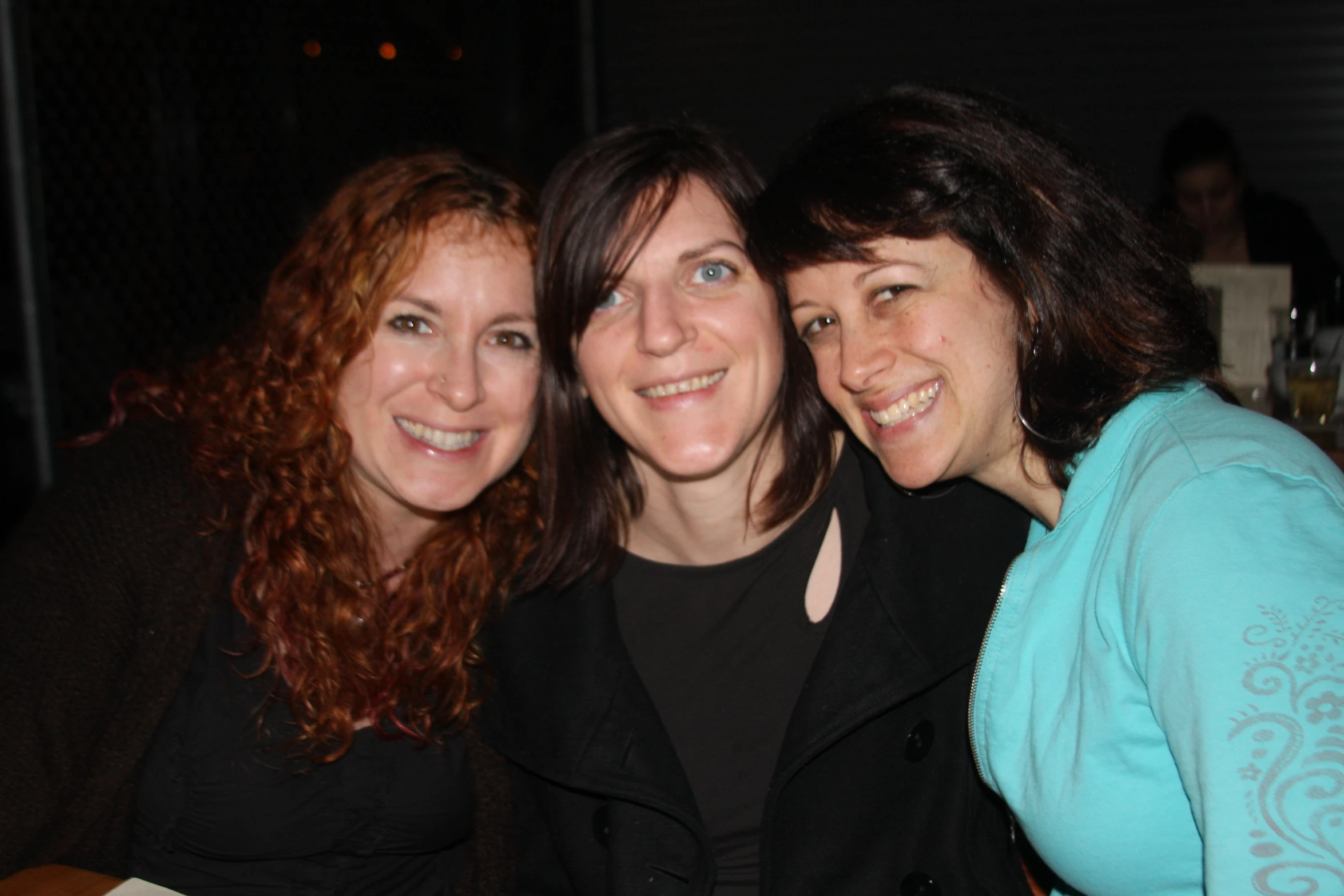 three women posing for a pograph with wine glasses