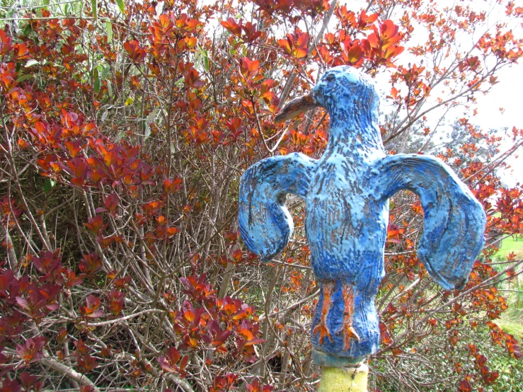 an odd looking stuffed animal in front of some red trees