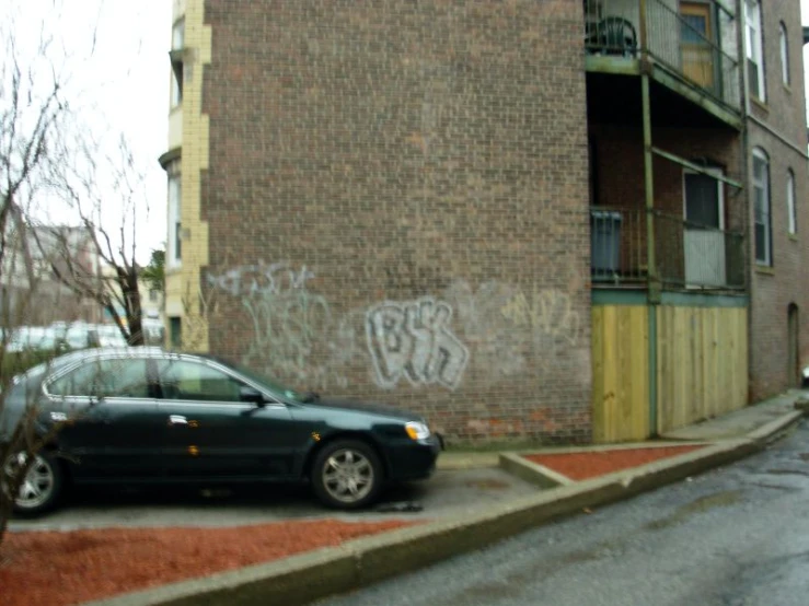 car parked by brick building with graffiti on the walls