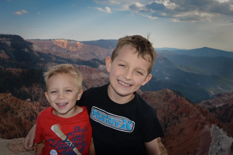 two children stand in front of some large mountains