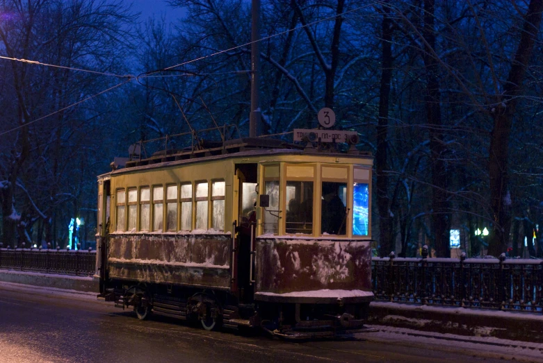 a old fashion trolley car is traveling down the road