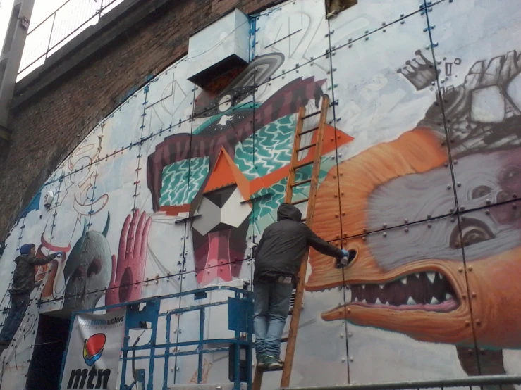 a man paints a mural on a building