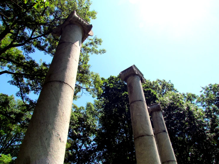 two pillared stone structures near trees and blue sky