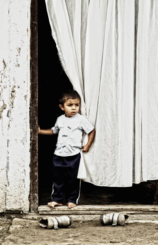 a little boy standing in the doorway to his home