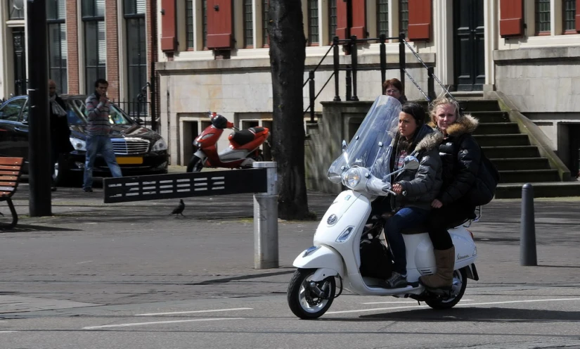 people on a motorbike on the street in front of the buildings