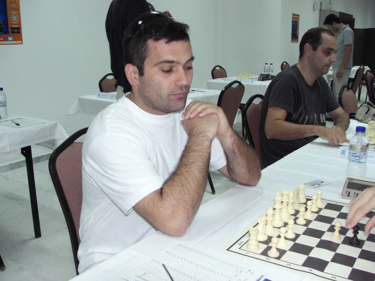 a man sitting at a table playing a game of chess