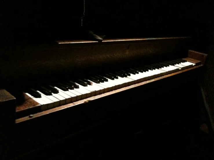 an old piano in a dark room with light from behind it