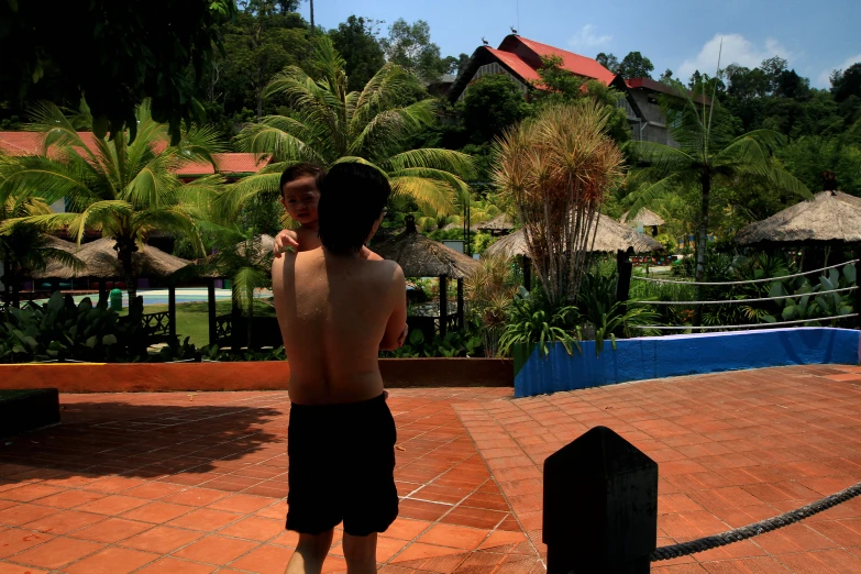 a man in black shorts is standing on the side of a swimming pool