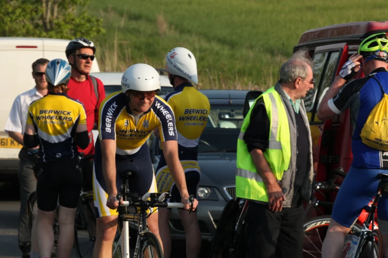 men in cycling helmets are talking while waiting for a bus