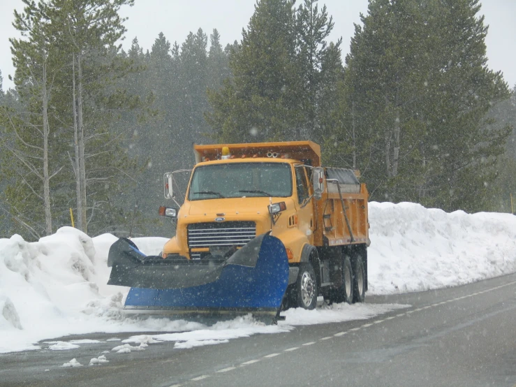 a truck with a plow attachment makes it's way down the road on a snowy day