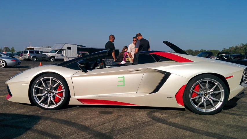 a group of people are gathered around a sports car