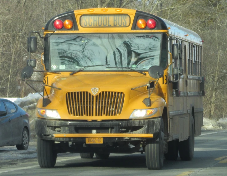 school bus stopped on a snowy street with a car nearby