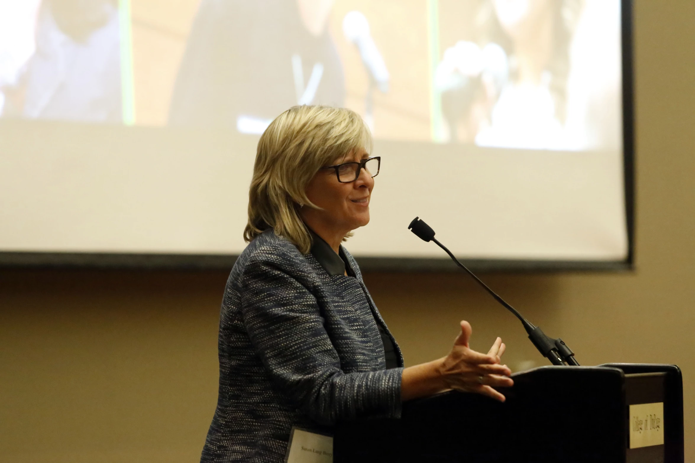 a woman stands at a podium during a presentation