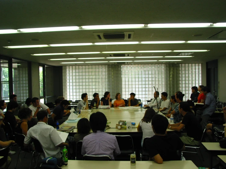 an office meeting room filled with people with laptops and papers on tables