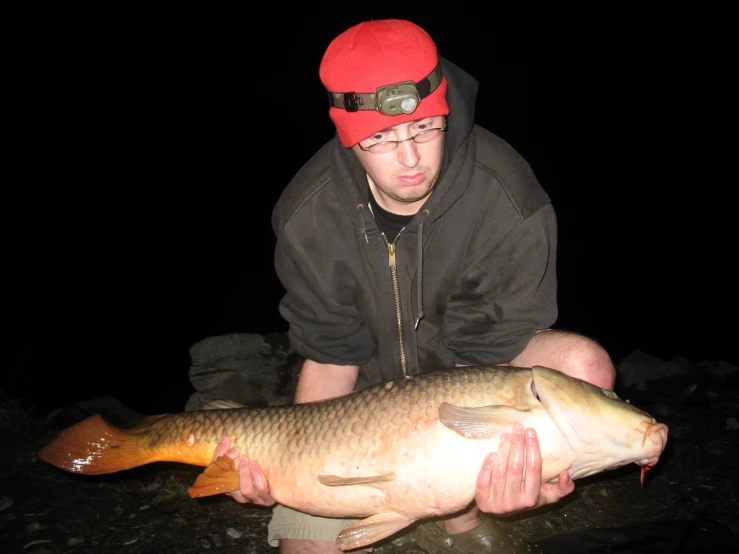 a man holding a fish up at night