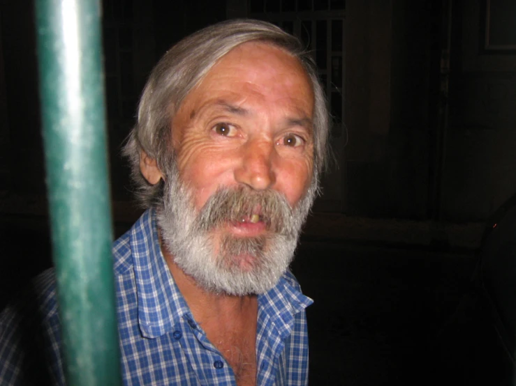 a man with graying hair wearing a blue plaid shirt and looking to the side