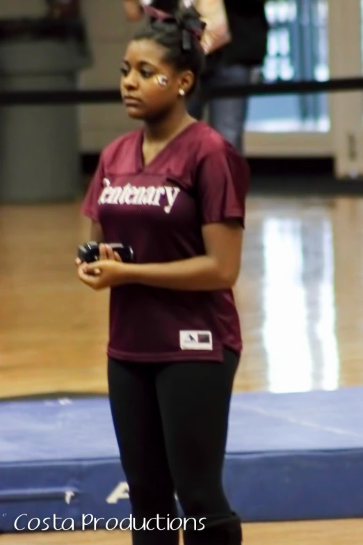 a woman standing on a hard wood floor holding a cell phone