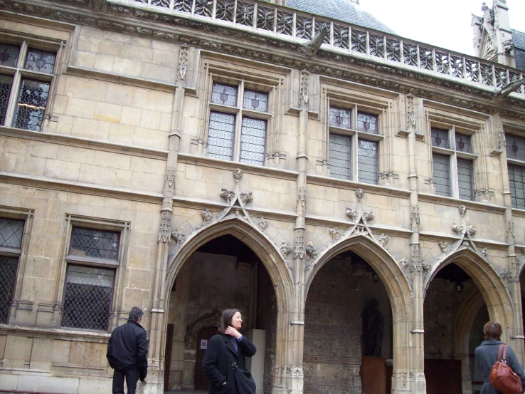 the woman is using her cell phone outside of an old building