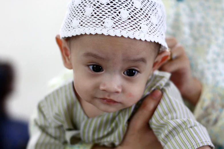 small child in hat being held by lady in dress