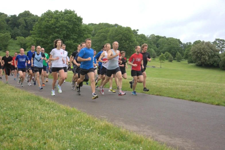 group of people jogging in park on asphalt road