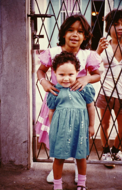 two small girls standing outside of a house