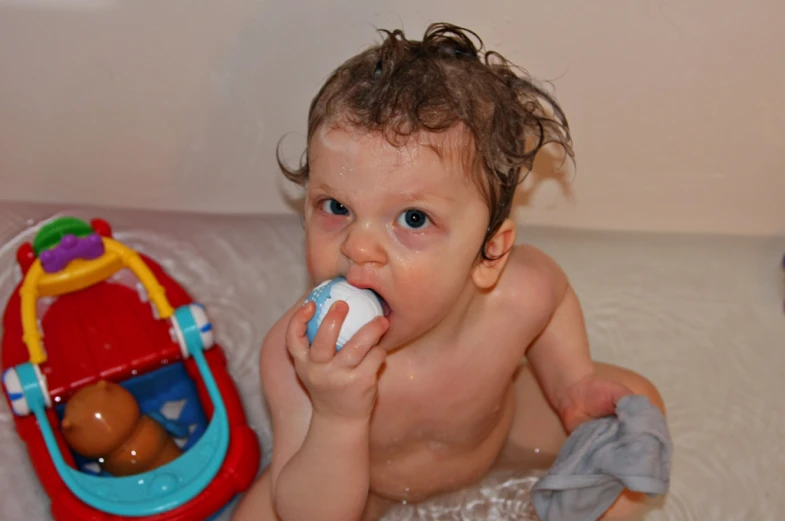 an adorable baby in a bathtub holding a toy