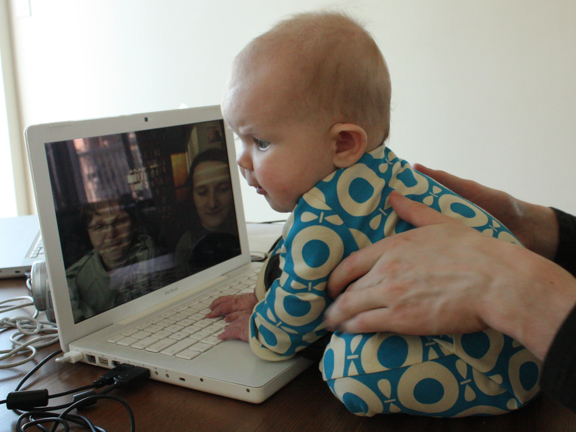 a baby being held by a man in front of a laptop computer