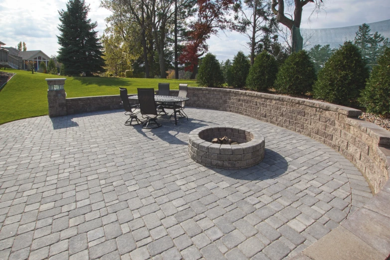 a patio that has a brick fire pit surrounded by grass