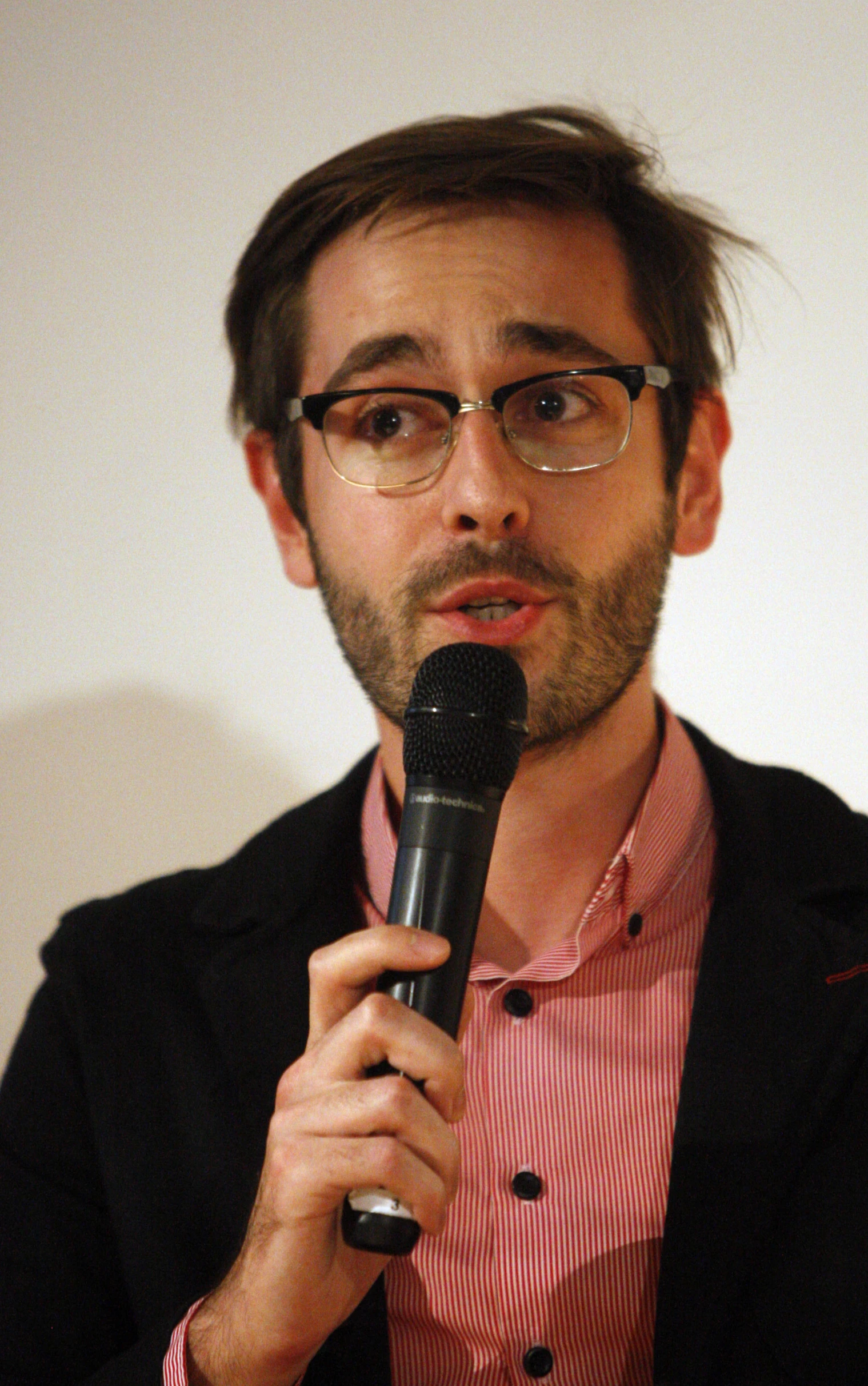 the man in glasses is talking on a microphone