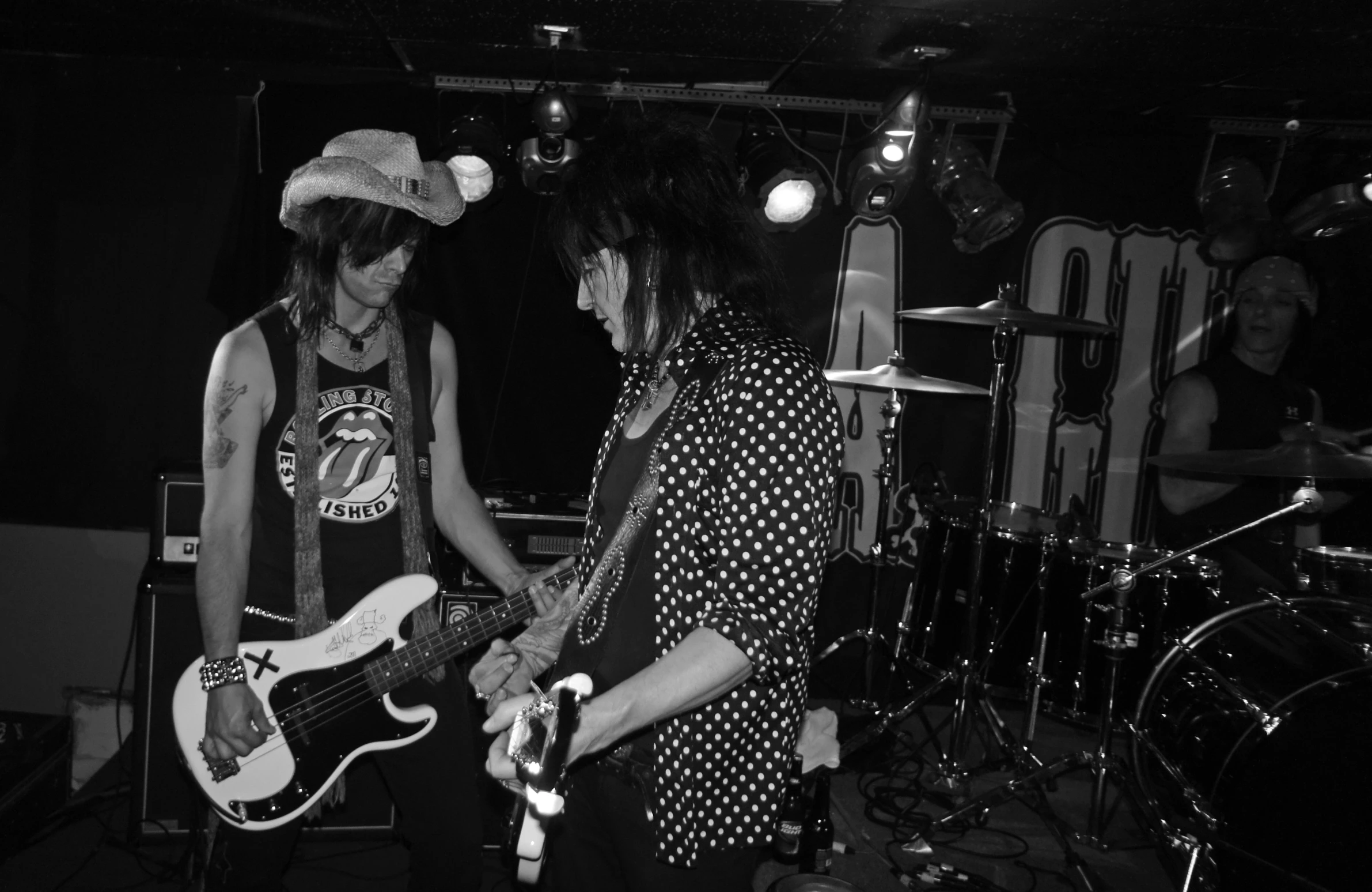 two people stand on stage playing guitars