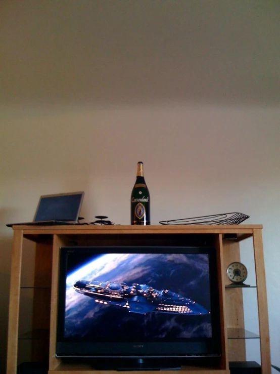 the television is on and there are a bottle on top of it