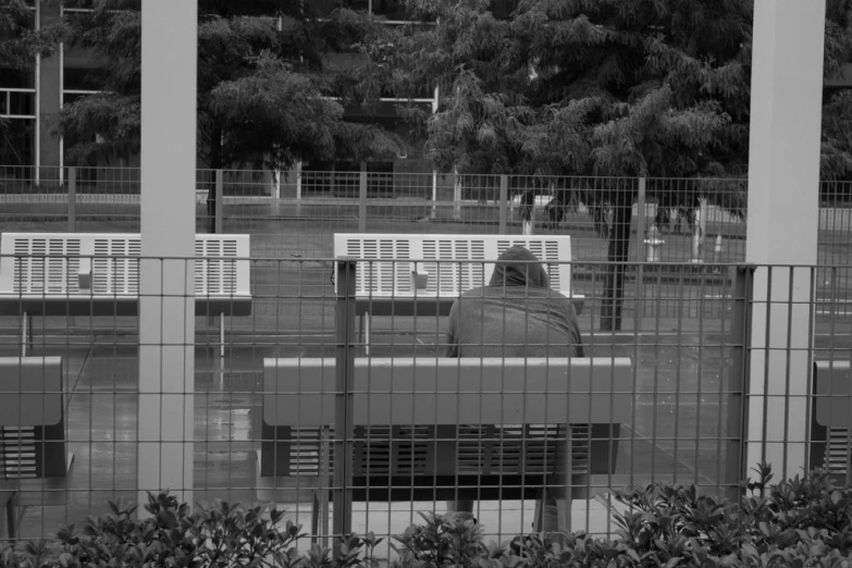 a person sitting on a bench between two pillars in a park