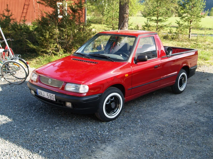 a red car with wheels and black tires is parked by some bicycles