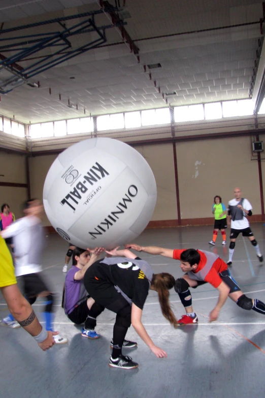 a group of people playing ball soccer indoors