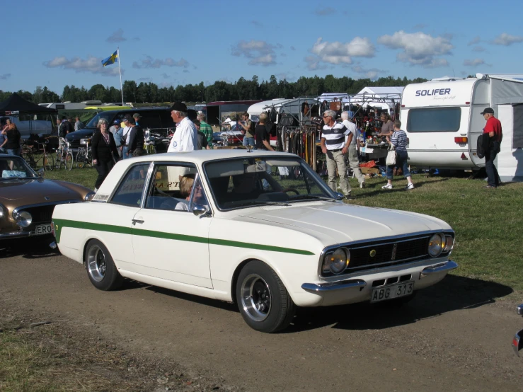 a white car with green trim and people walking around it