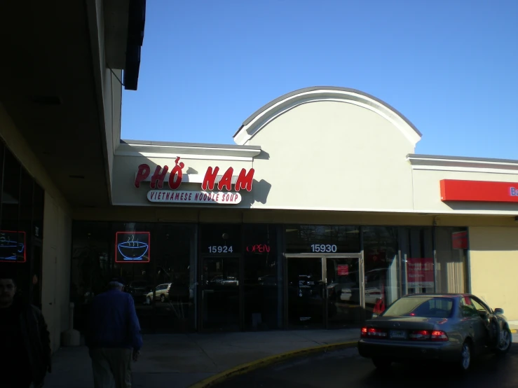 a man walking toward a pizza hut sitting on the street