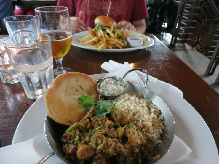 a plate with a meat and rice dish and a beer