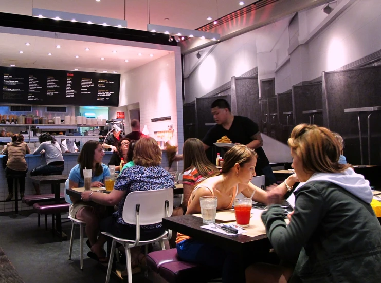 people eating and drinking at tables near an area with signs