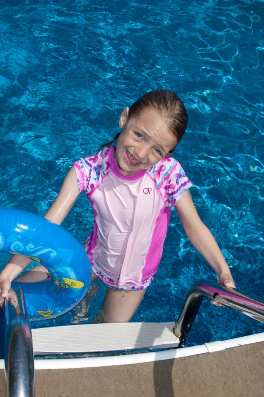 a small girl standing in a swimming pool