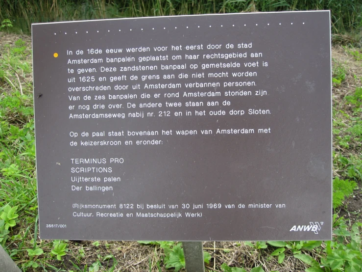 an information sign on a pole in front of grass