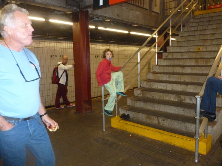 two men stand near some stairs, one is looking away