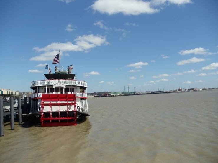 a large red and white boat sitting in a river