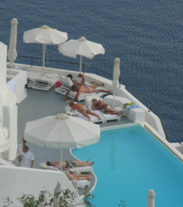 people sit at the pool on chairs and umbrellas