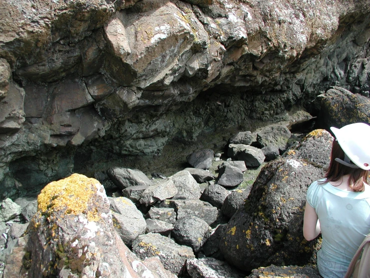 a woman in a hat walks near rocks