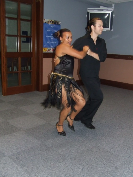 a woman in black dress dancing with a man in suit