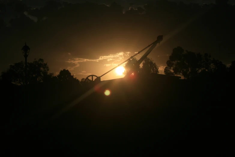 a crane working in the dark with trees and sky in background